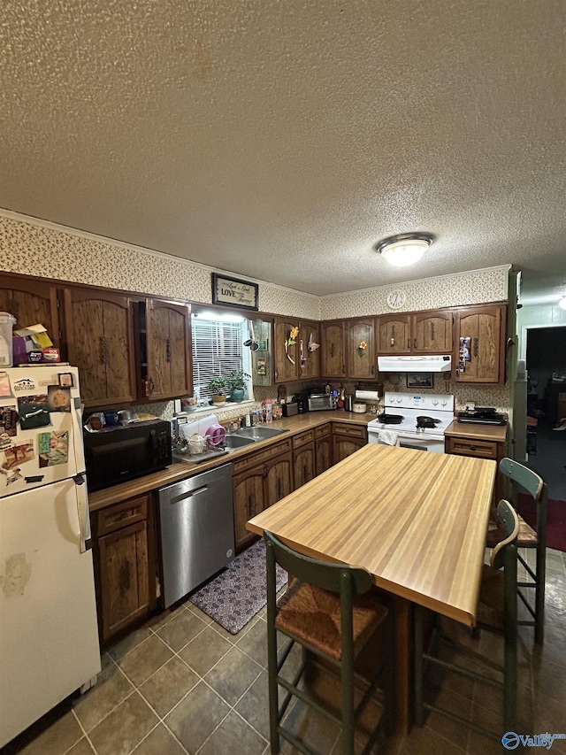 kitchen with dark brown cabinetry, white appliances, and a textured ceiling