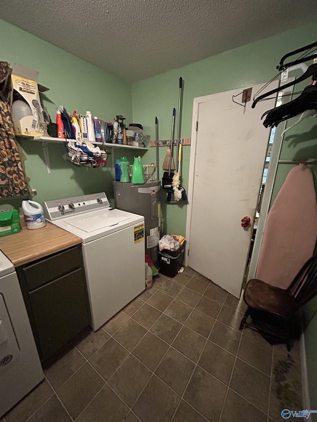 clothes washing area with washing machine and dryer, cabinets, electric water heater, a textured ceiling, and dark tile patterned flooring
