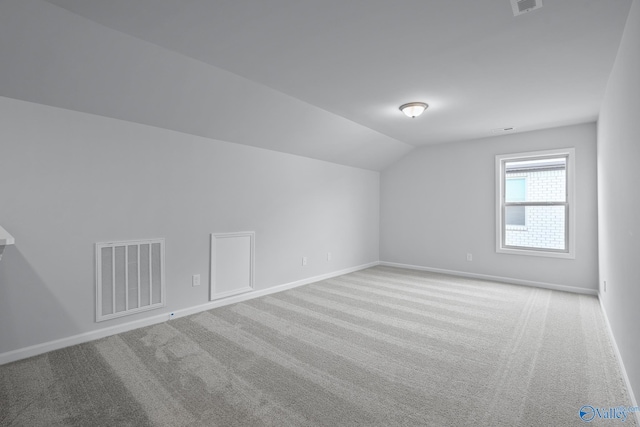 bonus room with light colored carpet and lofted ceiling