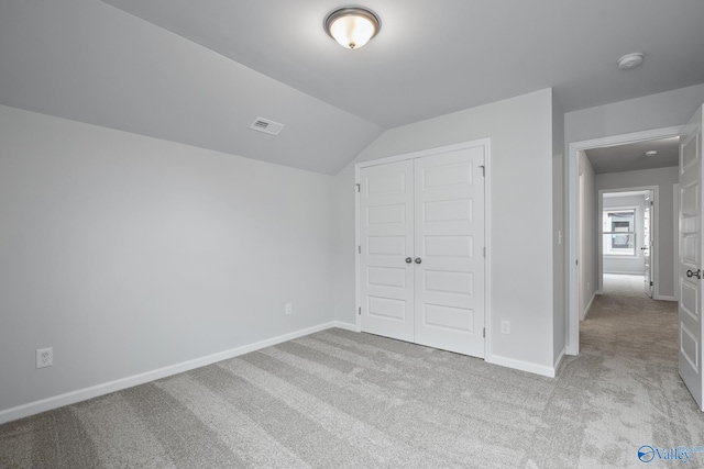 unfurnished bedroom with lofted ceiling, light carpet, and a closet