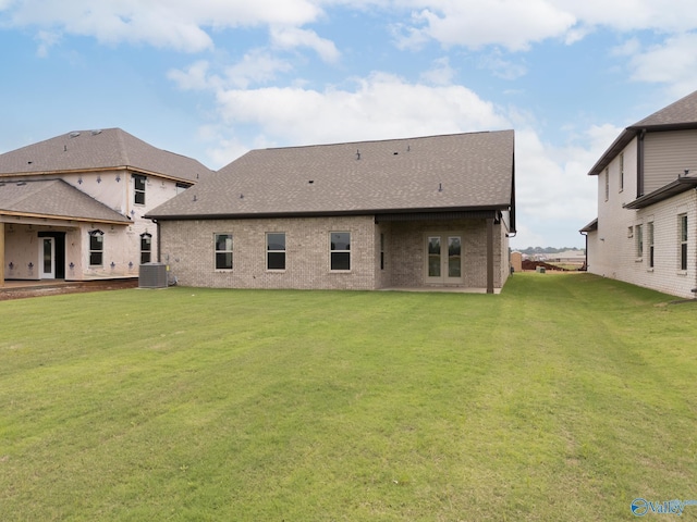 back of property featuring central AC unit and a lawn