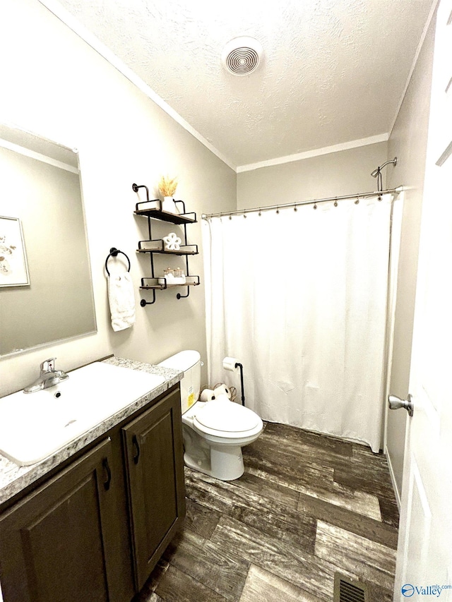 bathroom with visible vents, crown molding, vanity, and wood finished floors