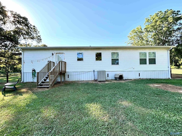 rear view of house featuring cooling unit and a yard