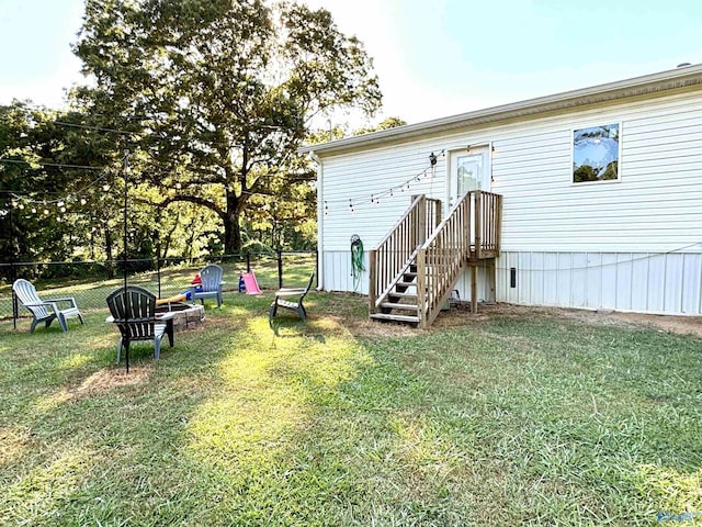 back of house with a yard, fence, and a fire pit