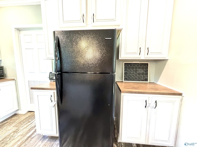 kitchen featuring light wood-style flooring, wood counters, freestanding refrigerator, and white cabinetry