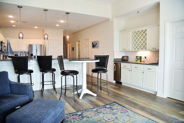 kitchen with stainless steel refrigerator with ice dispenser, decorative light fixtures, a kitchen breakfast bar, a kitchen island, and white cabinets