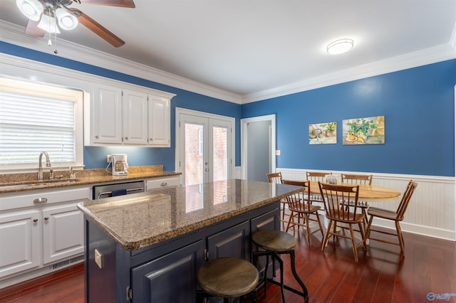 kitchen featuring dark stone countertops, white cabinets, a center island, ceiling fan, and sink