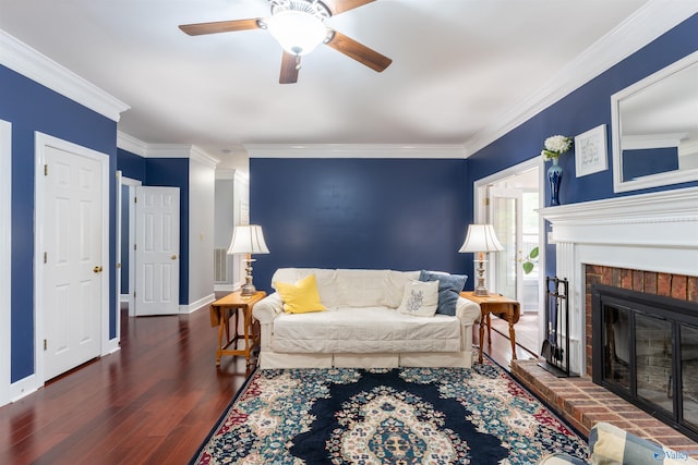 living room featuring crown molding, ceiling fan, dark wood-type flooring, and a brick fireplace