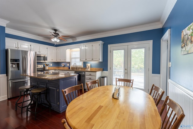 dining room featuring dark wood-type flooring, sink, ornamental molding, ceiling fan, and french doors