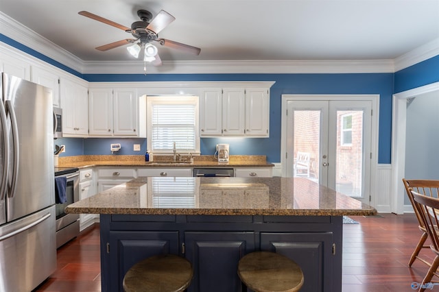 kitchen with ceiling fan, white cabinets, plenty of natural light, stainless steel appliances, and a center island