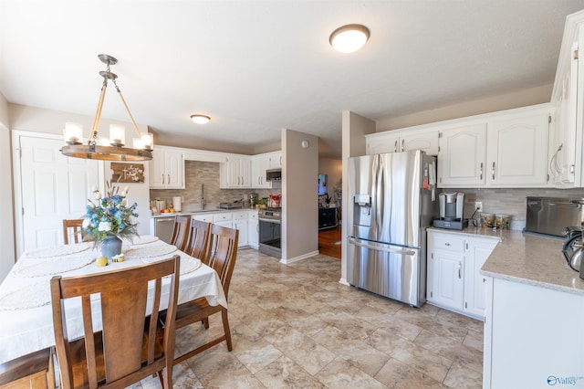 kitchen with stainless steel appliances, light stone countertops, hanging light fixtures, and white cabinets