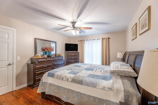 bedroom featuring ceiling fan, a textured ceiling, and dark hardwood / wood-style flooring