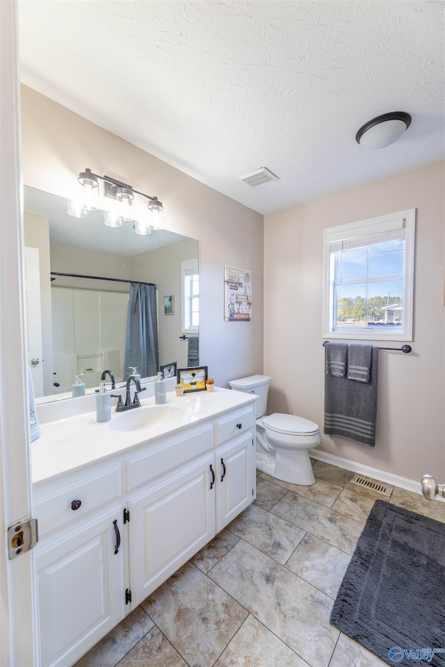 bathroom with a shower with curtain, a healthy amount of sunlight, toilet, and vanity