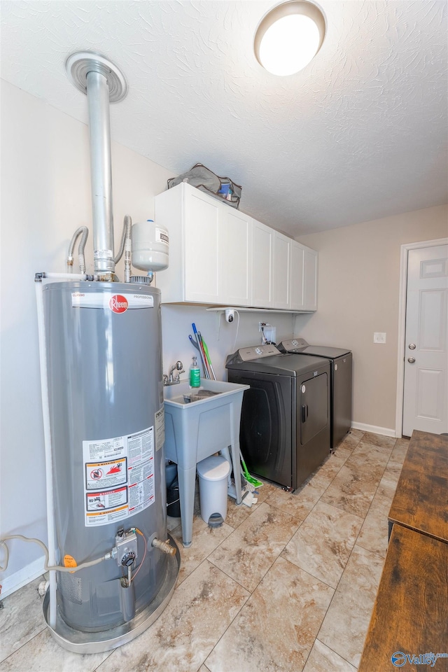 clothes washing area featuring sink, gas water heater, cabinets, separate washer and dryer, and a textured ceiling