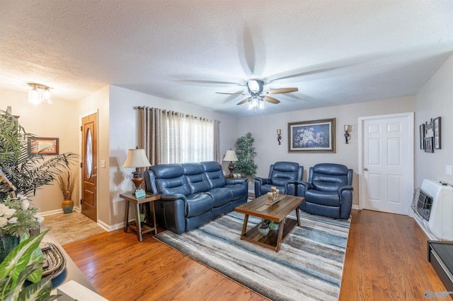 living room with ceiling fan, hardwood / wood-style floors, heating unit, and a textured ceiling