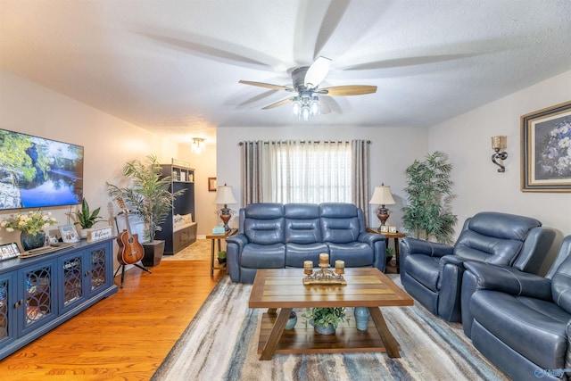 living room featuring ceiling fan, hardwood / wood-style floors, and a textured ceiling