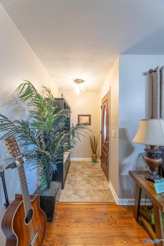 hall with a textured ceiling and light hardwood / wood-style floors