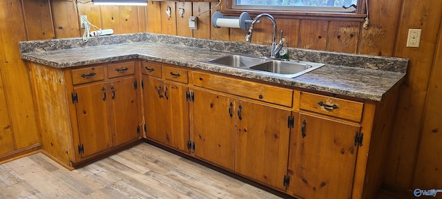 kitchen featuring sink, light hardwood / wood-style flooring, and wood walls