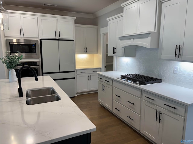 kitchen with light stone counters, white cabinets, dark hardwood / wood-style flooring, stainless steel appliances, and sink