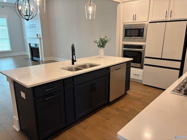 kitchen featuring appliances with stainless steel finishes, a center island with sink, sink, and a notable chandelier