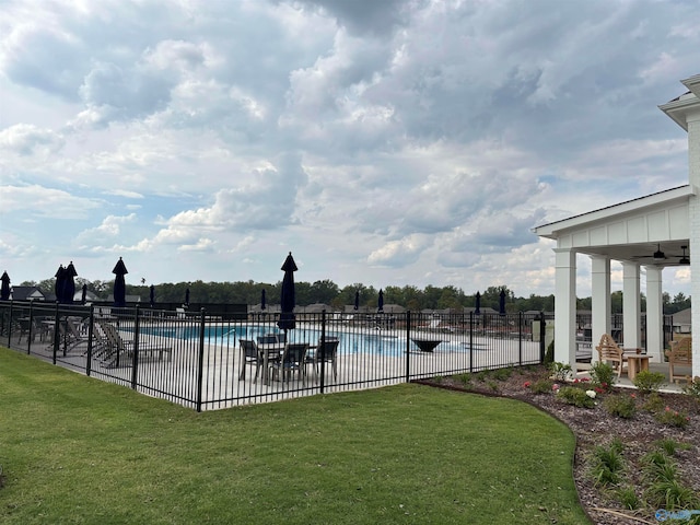 view of swimming pool featuring a yard and ceiling fan