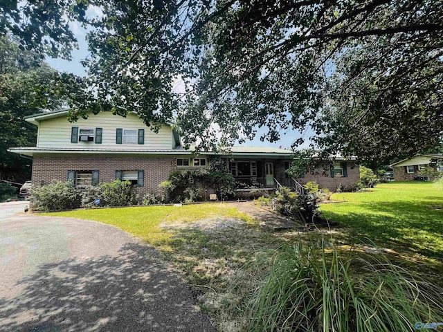 split level home with brick siding, a porch, and a front yard