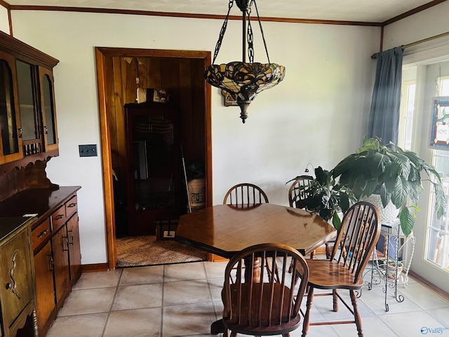 dining space with light tile patterned floors, crown molding, and baseboards