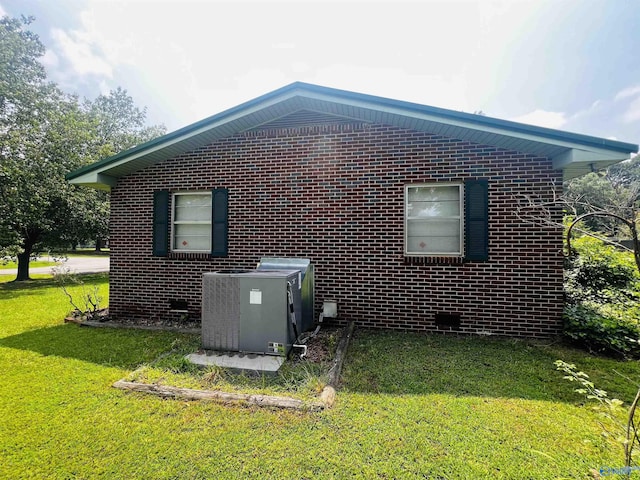 view of property exterior featuring brick siding, central AC unit, and a yard