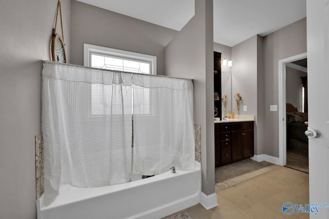 ensuite bathroom with shower / bath combination with curtain, tile patterned flooring, vanity, and baseboards