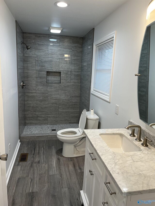 212 Nelson St NW, Hartselle, AL 35640 - bathroom with toilet, a tile shower, hardwood / wood-style floors, and vanity