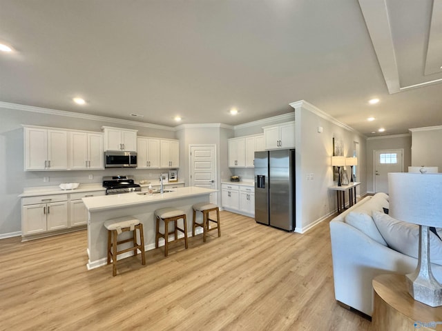 kitchen with white cabinets, a center island with sink, sink, light hardwood / wood-style floors, and stainless steel appliances