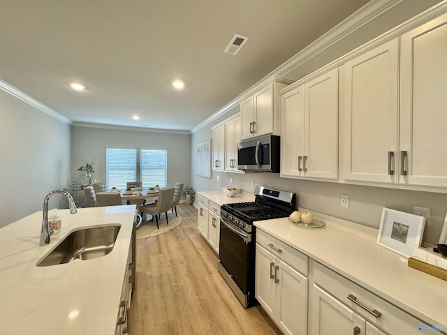 kitchen with sink, stainless steel appliances, crown molding, white cabinets, and light wood-type flooring