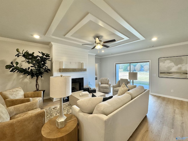 living room featuring a fireplace, wood-type flooring, ceiling fan, and crown molding