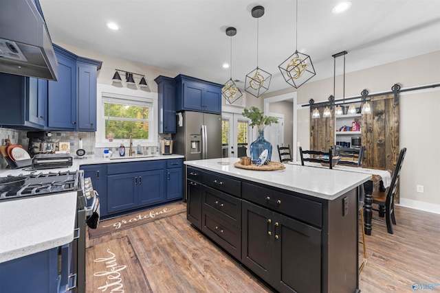 kitchen featuring sink, hanging light fixtures, dark wood-type flooring, a barn door, and appliances with stainless steel finishes