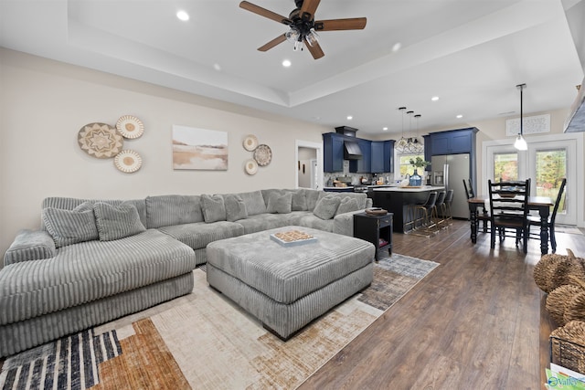 living room featuring a tray ceiling, ceiling fan, and dark hardwood / wood-style flooring