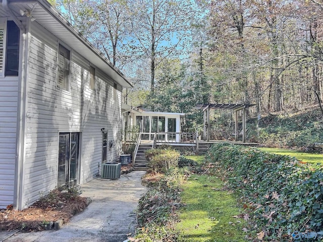 view of yard with a pergola, central air condition unit, a deck, and a sunroom