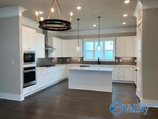 kitchen with dark hardwood / wood-style flooring, white cabinetry, backsplash, and wall chimney range hood