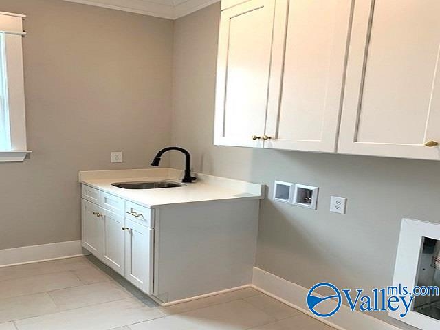 washroom featuring sink, washer hookup, light tile patterned floors, and cabinets