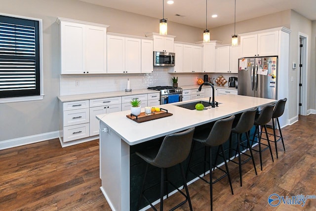 kitchen with appliances with stainless steel finishes, sink, a center island with sink, and white cabinets