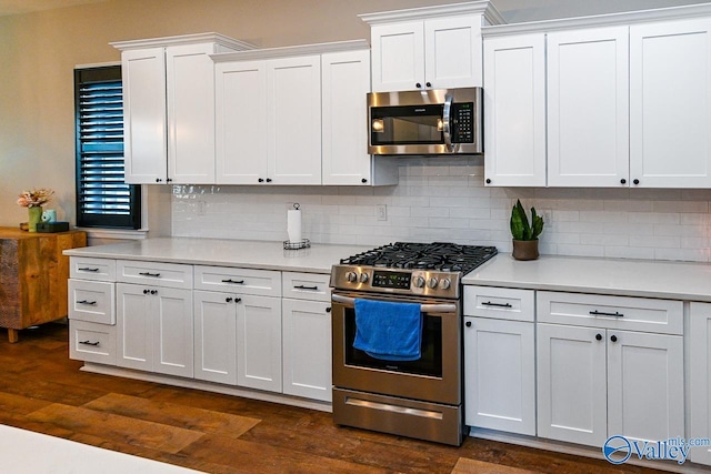 kitchen with appliances with stainless steel finishes, white cabinets, dark hardwood / wood-style flooring, and decorative backsplash