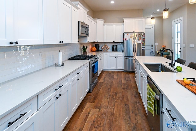 kitchen with sink, appliances with stainless steel finishes, dark hardwood / wood-style floors, pendant lighting, and white cabinets