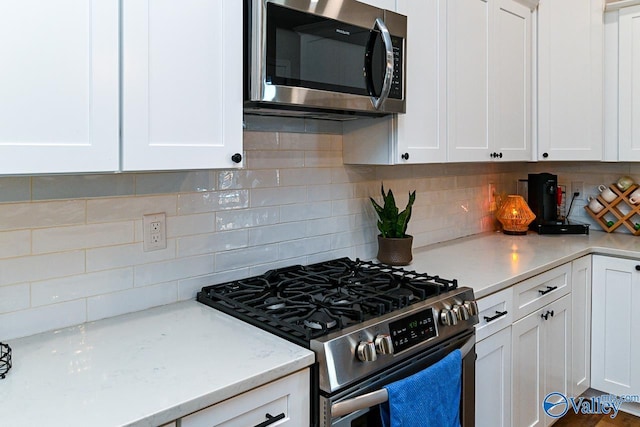 kitchen featuring stainless steel appliances, white cabinets, and decorative backsplash