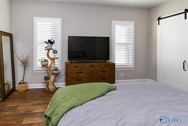 bedroom with a barn door and dark hardwood / wood-style flooring