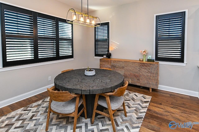 dining space with wood-type flooring and an inviting chandelier