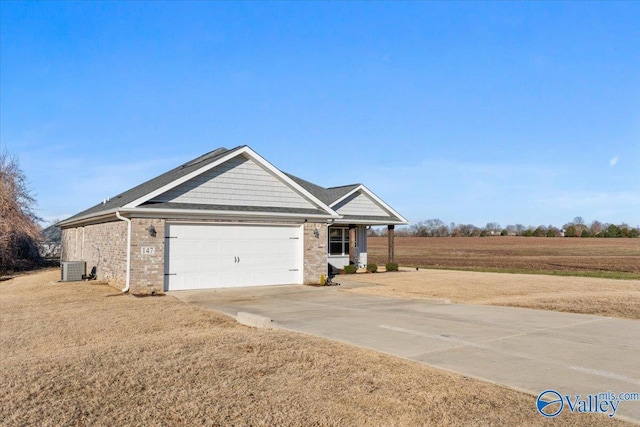 view of front of home with central air condition unit, a rural view, a front yard, and a garage