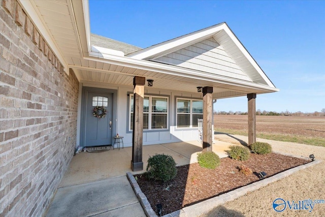 view of exterior entry with covered porch and a rural view