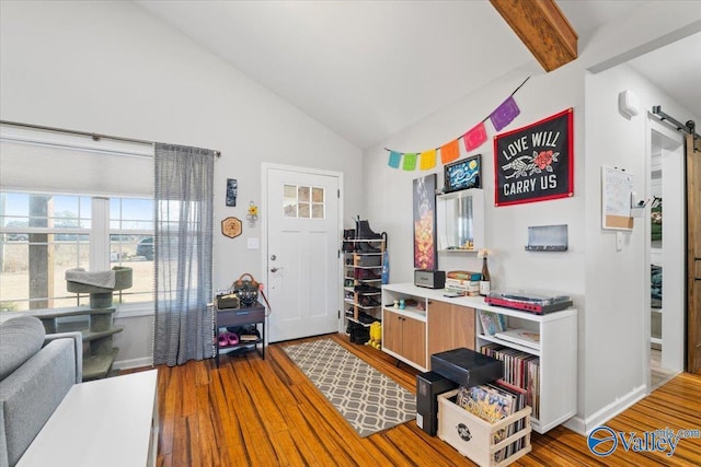 office featuring lofted ceiling with beams, a barn door, and wood-type flooring