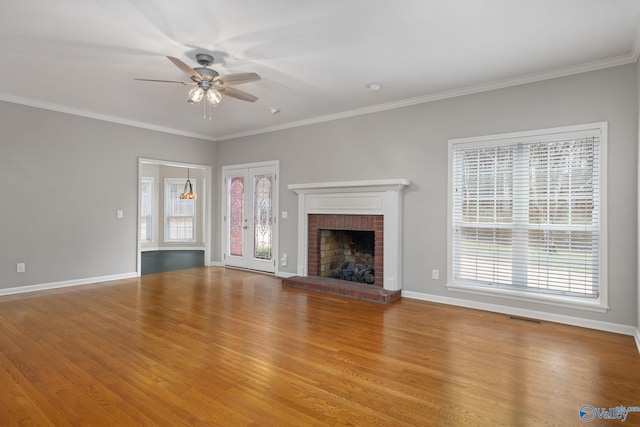 unfurnished living room featuring crown molding, a fireplace, ceiling fan, and light wood-type flooring