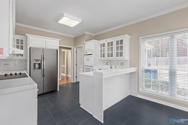 kitchen with white cabinetry, tile countertops, stainless steel fridge with ice dispenser, kitchen peninsula, and black electric stovetop