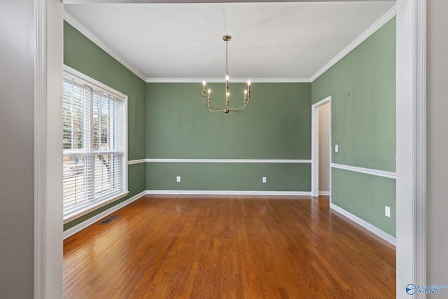 spare room with crown molding, hardwood / wood-style flooring, and a notable chandelier